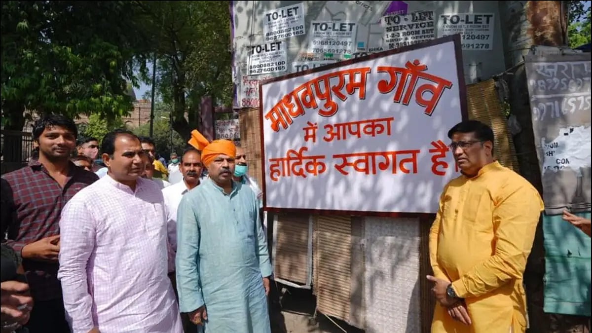 Delhi BJP president Adesh Gupta alongside a board ‘Welcome to Madhavpuram’