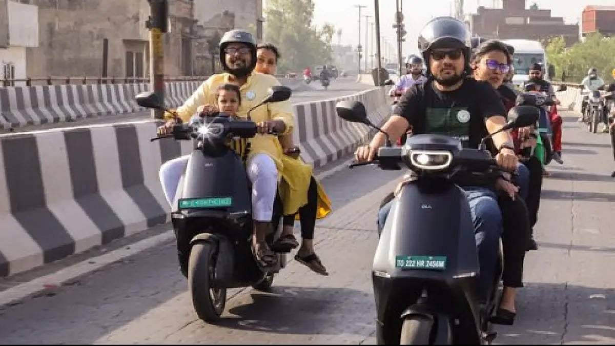 People riding Ola electric scooters