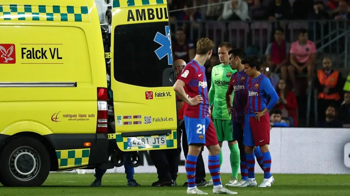 Barcelona players react as their teammate Ronald Araujo is carried by an ambulance after injury.