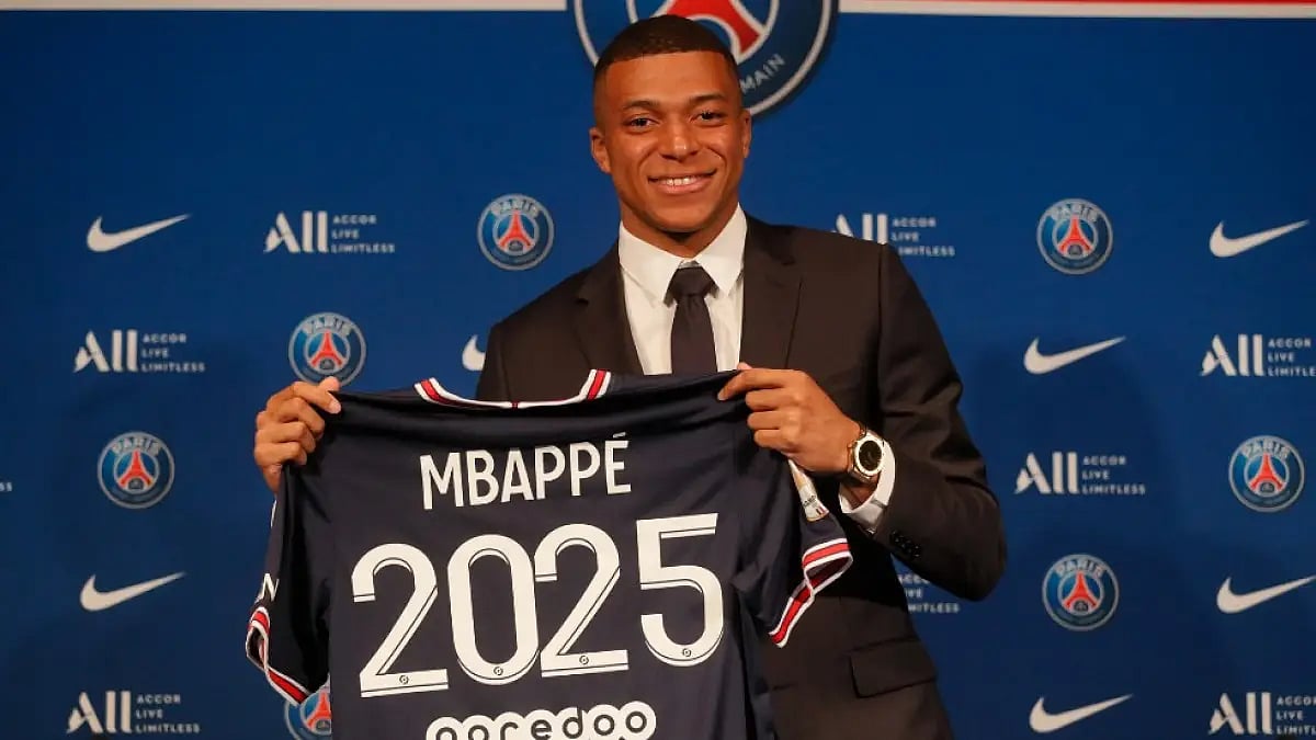 Kylian Mbappe poses for a picture after signing a new threeyear deal with PSG.