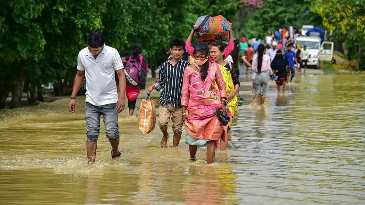 People walking through a waterlogged area in flood-hit Nagaon district in Assam
