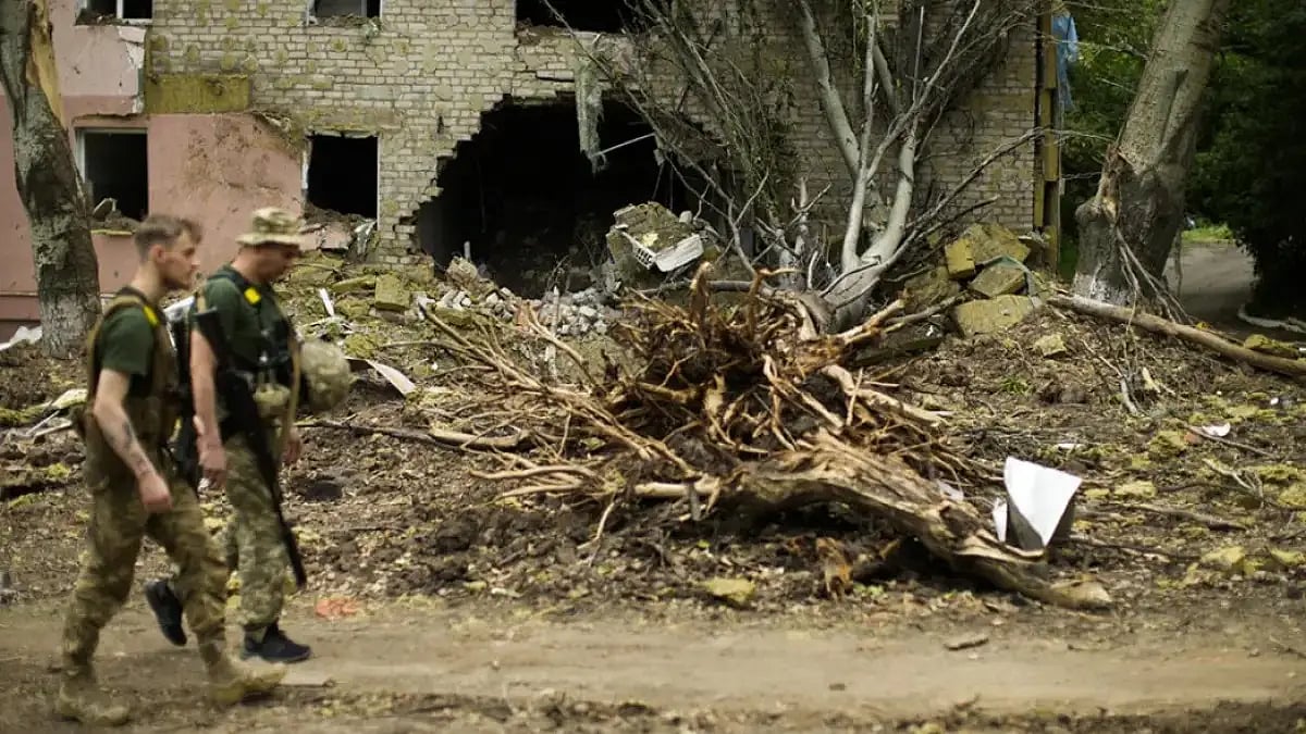 Soldiers walking in front of a building a tree uprooted in the Ukraine war