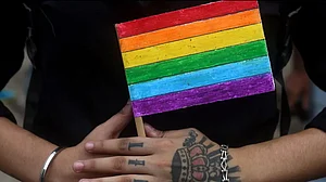 A person holds the Rainbow Flag, a symbol of the LGBTQ community
