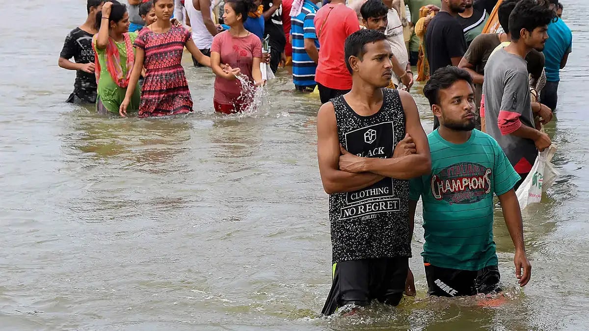 Villagers wade through a flooded street after heavy rainfall, at Kalita Kuchi in Kamrup district.
