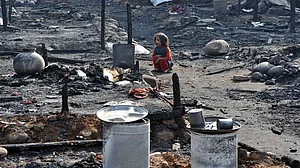 A Myanmar refugee lady looks for belongings after a fire at slum area outskirts of Jammu |