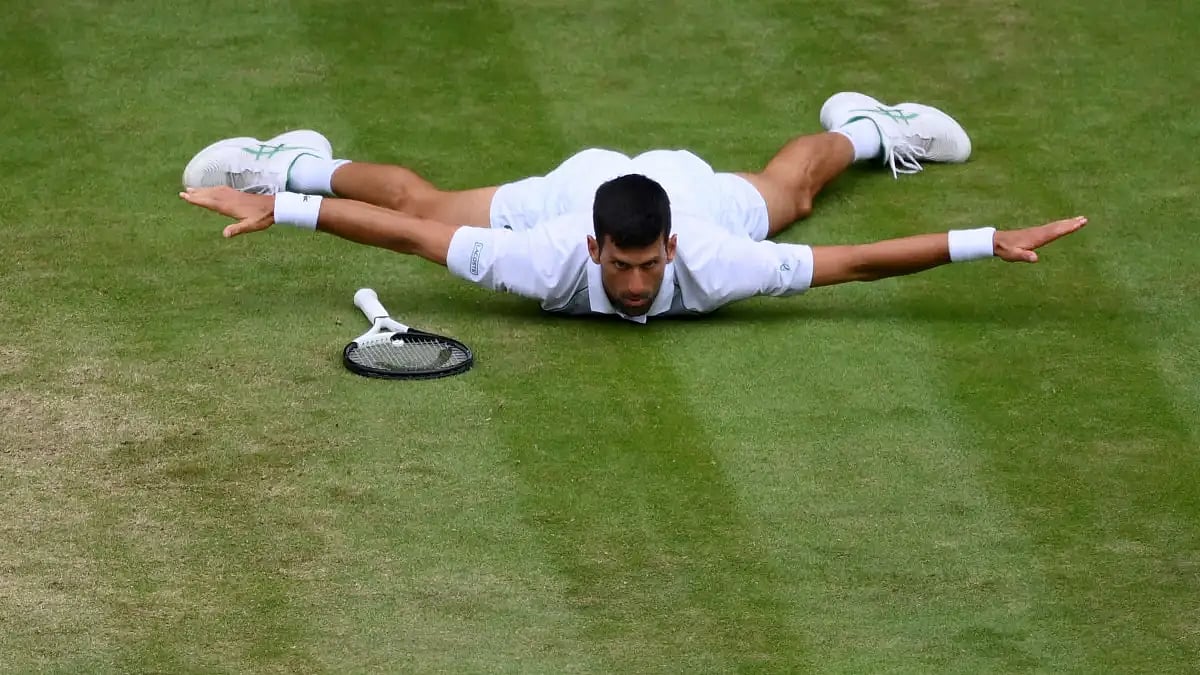 Novak Djokovic reacts after hitting an acrobatic passing shot past Jannik Sinner during the Wimbledon quarterfinals.