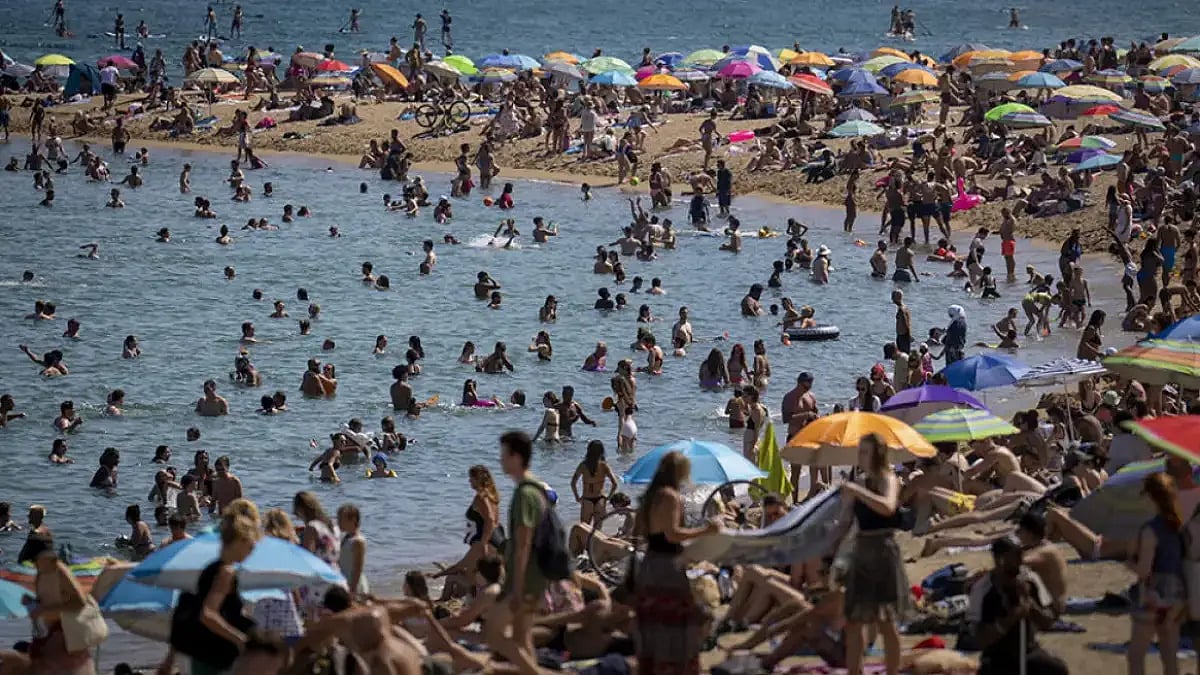 People cool off in the water on a hot and sunny day at the beach in Barcelona, Spain.