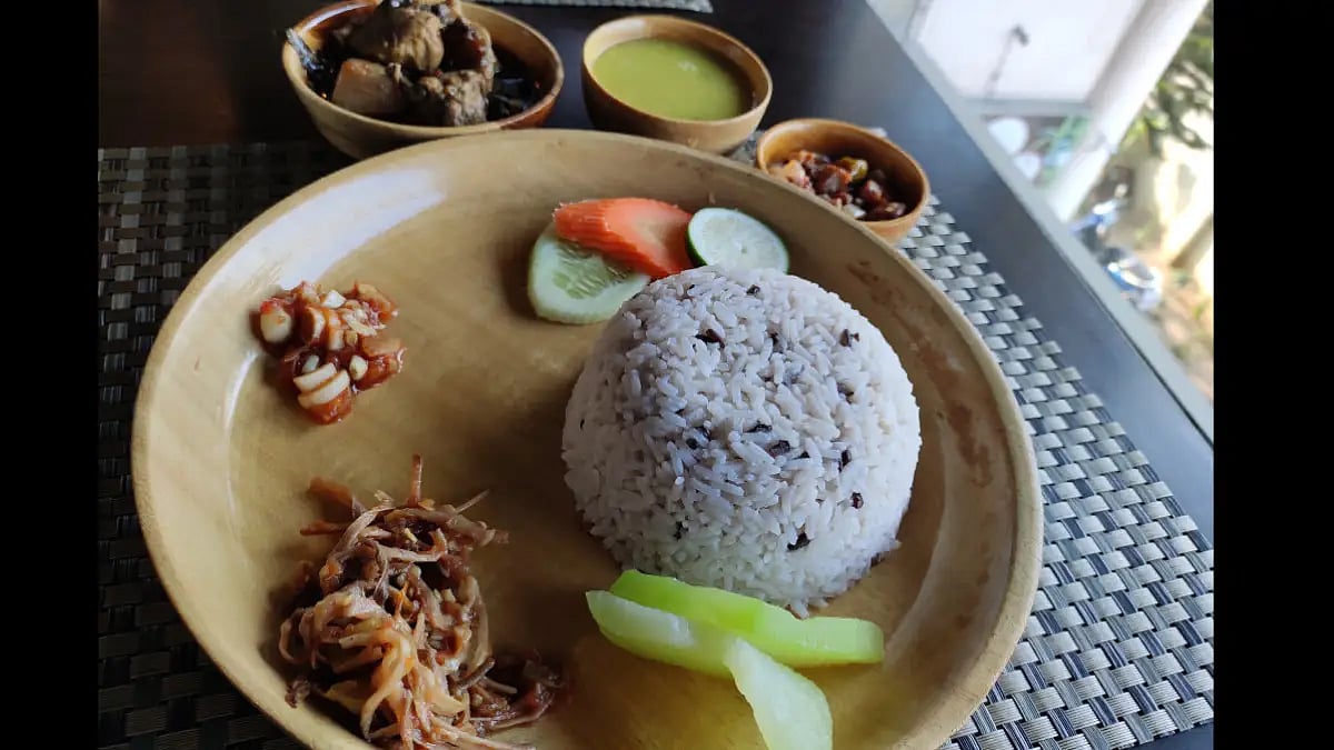 An ethnic Naga meal consisting of steamed rice mixed with black rice, vegetables, chutneys, dal, and