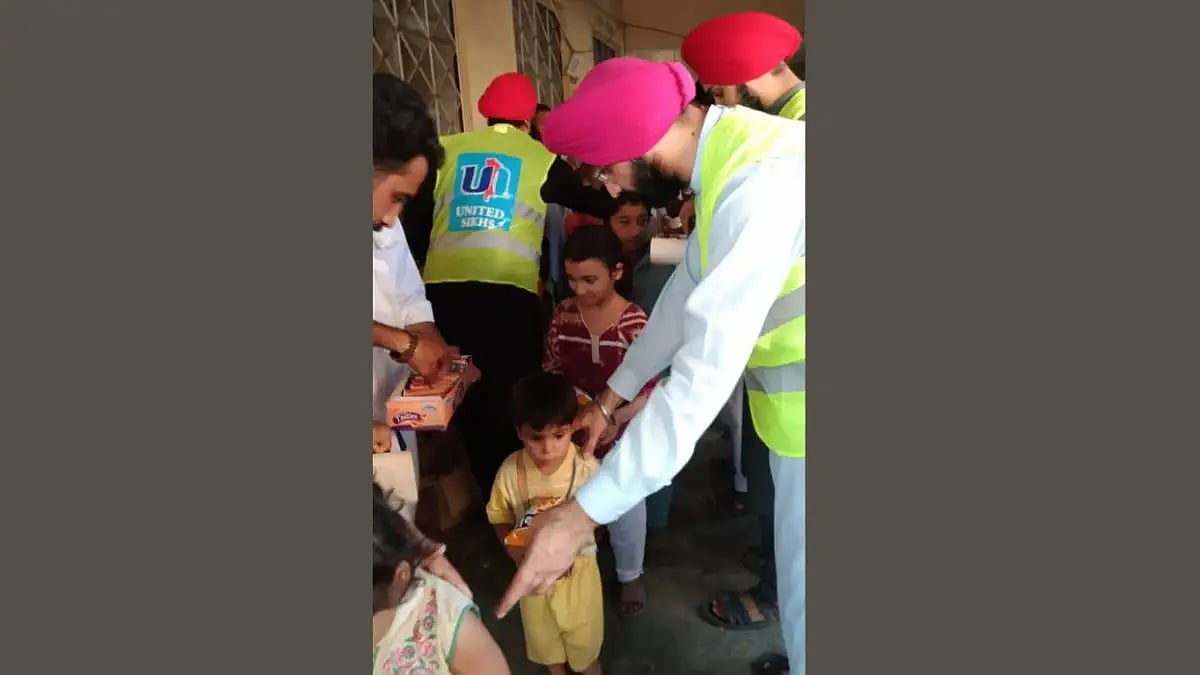 The volunteers of the United Sikhs organization distribute food items to the people in flood-hit are