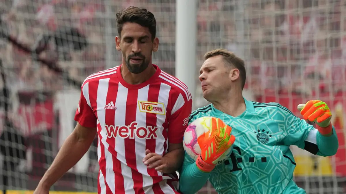 Bayern Munich goalkeeper Manuel Neuer and Union Berlin's Rani Khedira challenge for the ball.