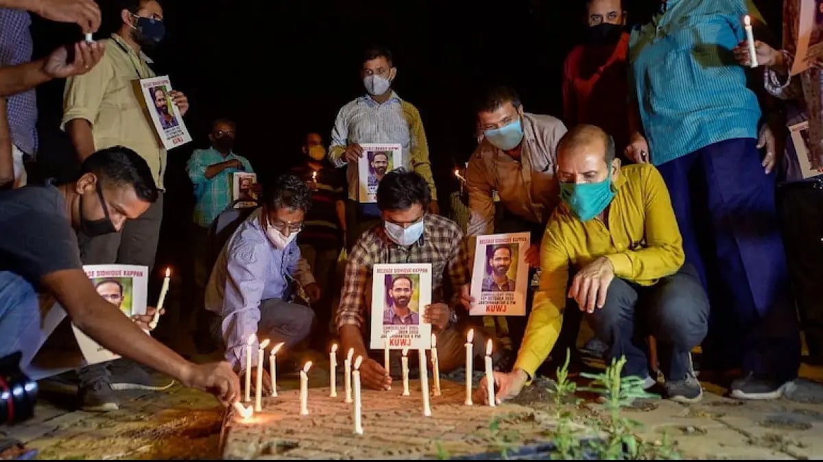 People light candles in front of Siddique Kappan's posters. 