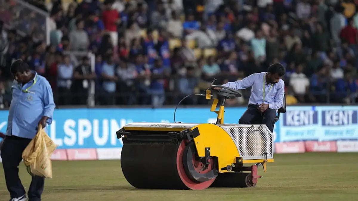 Groundsmen work on the wet patches of the field.