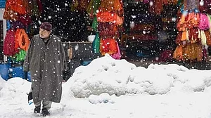 A man walks infront of yarn shop amid fresh snowfall in downtown area of Srinagar