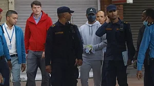 Sandeep Lamichhane (in grey) is being taken by police after landing in Kathmandu.