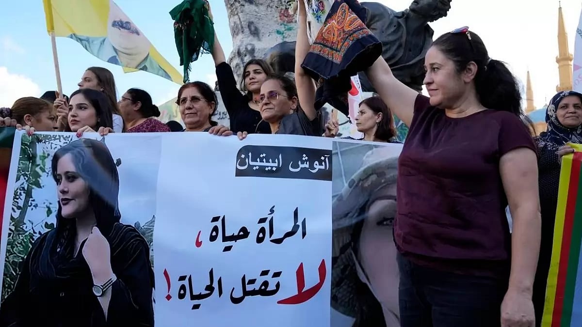 Kurdish women activists hold headscarfs and a poster of Mahsa Amini