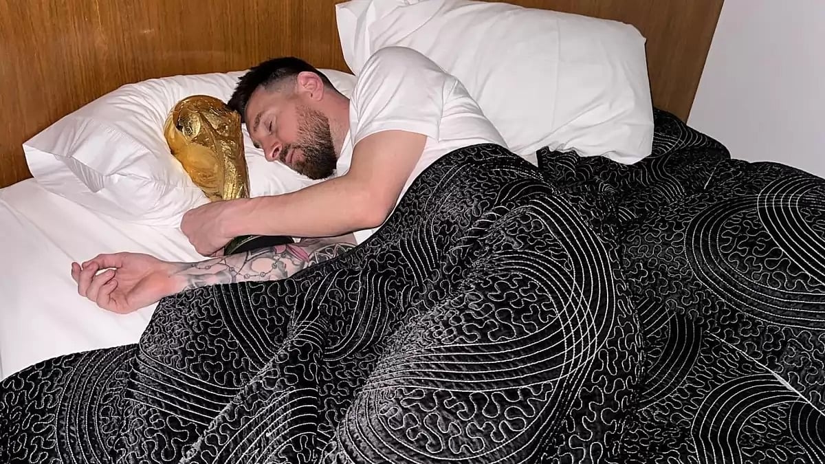 Lionel Messi sleeping with the FIFA trophy besides him.