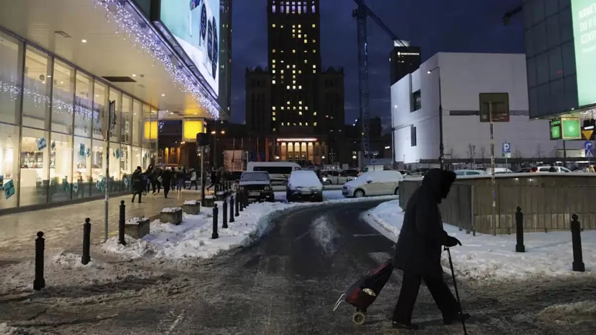 A woman carrying a shopping cart walks in Warsaw's downtown, Poland, Tuesday, Dec. 13, 2022. 