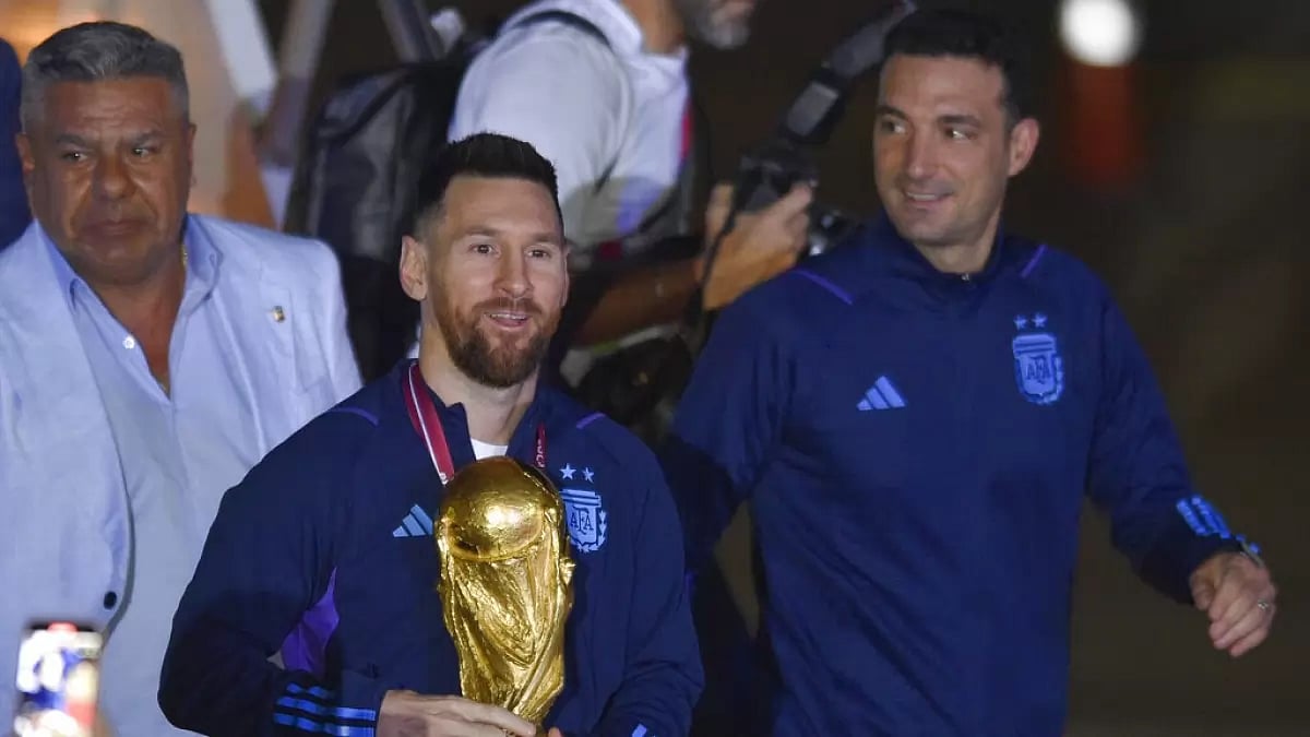 Messi, left, holds the World Cup trophy as he arrives in Buenos Aires with coach Scaloni, right.