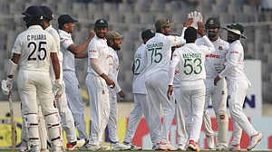 Bangladesh cricketers celebrate Pujara's wicket as India batters wait for an official ruling.