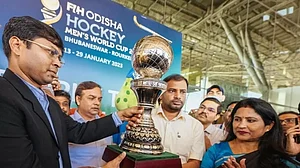 Hockey India President Dilip Tirkey gives the trophy to state's Sports Minister Tusharkanti Behera.
