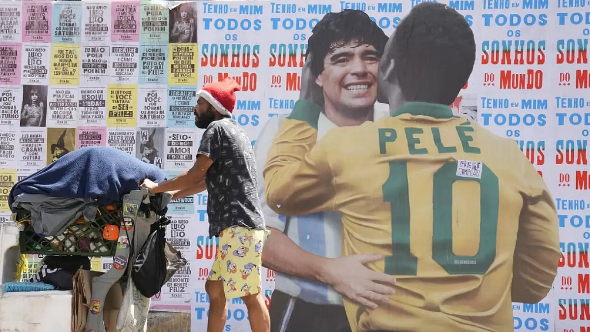 A passerby walks past a mural of Pele hugging Diego Maradona.