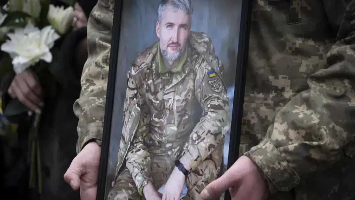 A Ukrainian serviceman holds the photo of his comrade in Kyiv, Ukraine, Tuesday, Dec. 27, 2022.