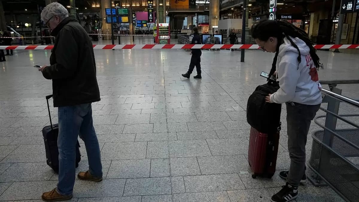 People stand near a tape put up by authorities after a stabbing attack at a Paris train station