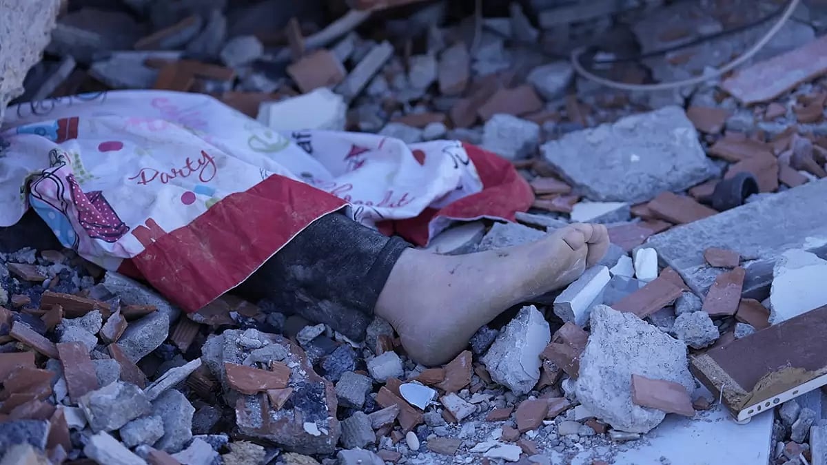 The foot of a dead child is seen under a destroyed building in Turkey after the magnitude 7.8 earthquake