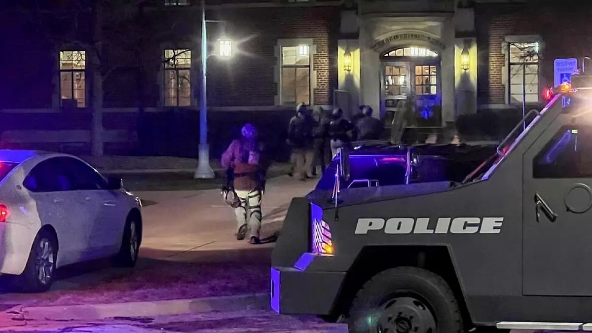 Armed police officers with weapons drawn rush into Phillips Hall at Michigan State University.