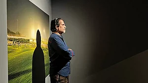 The Fourth State: Sudarshan Shetty standing in front of Sleepers, a photograph by Dhruv Malhotra at the Serendipity Arts Festival 2022, Goa