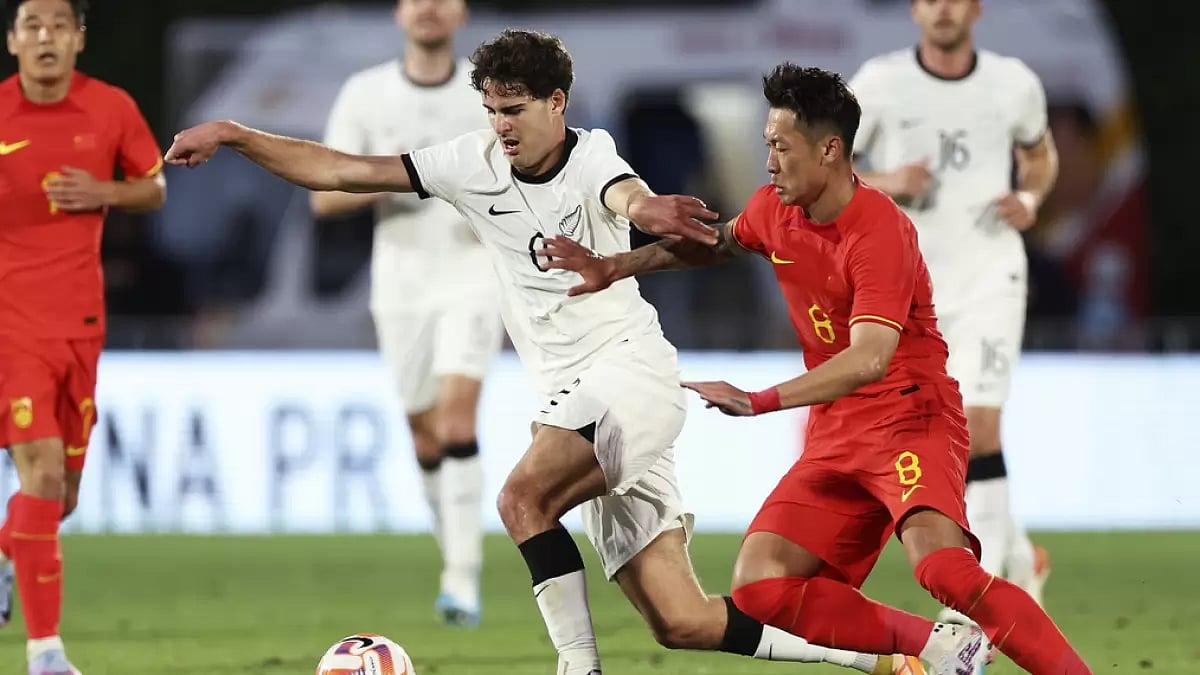 Matthew Garbett, centre, and Xin Xu compete for the ball in their teams' friendly.