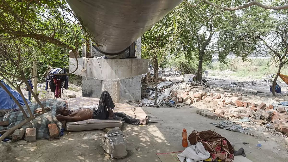 People sleep beneath a pipeline along Yamuna ghat after their shelters were broken.