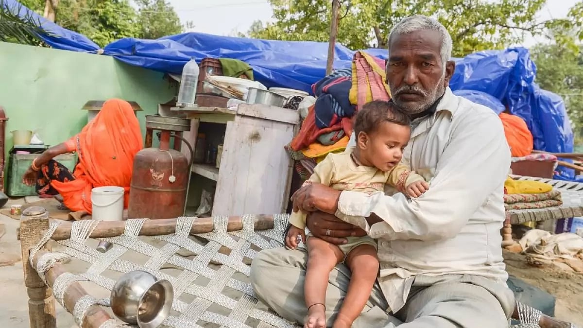 An old man sits tight with his grandson after their homes were demolished ahead of G20 summit