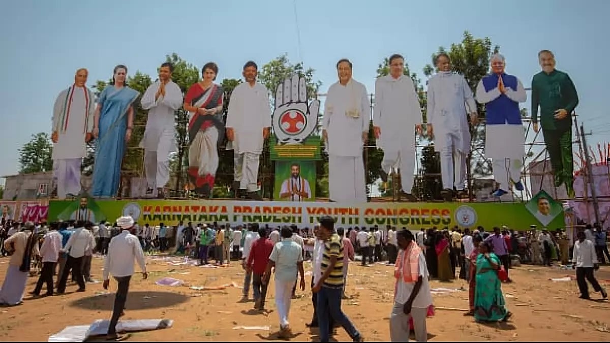 Supporters walk next to giant cutouts of Congress leaders at a rally in Kolar