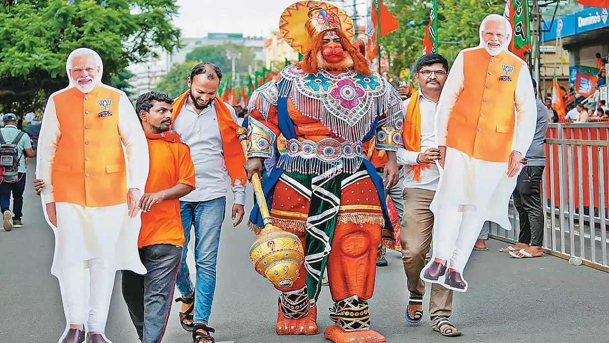 In the Naataka of Democracy: Cut-outs of Narendra Modi flank a supporter dressed as the mythical god, Hanuman, on the streets of Bengaluru