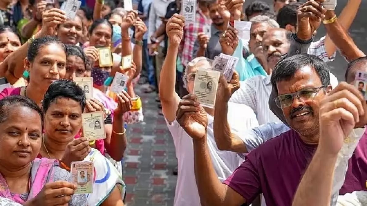 Voters standing in a queue outside a poling booth showing their voter cards.