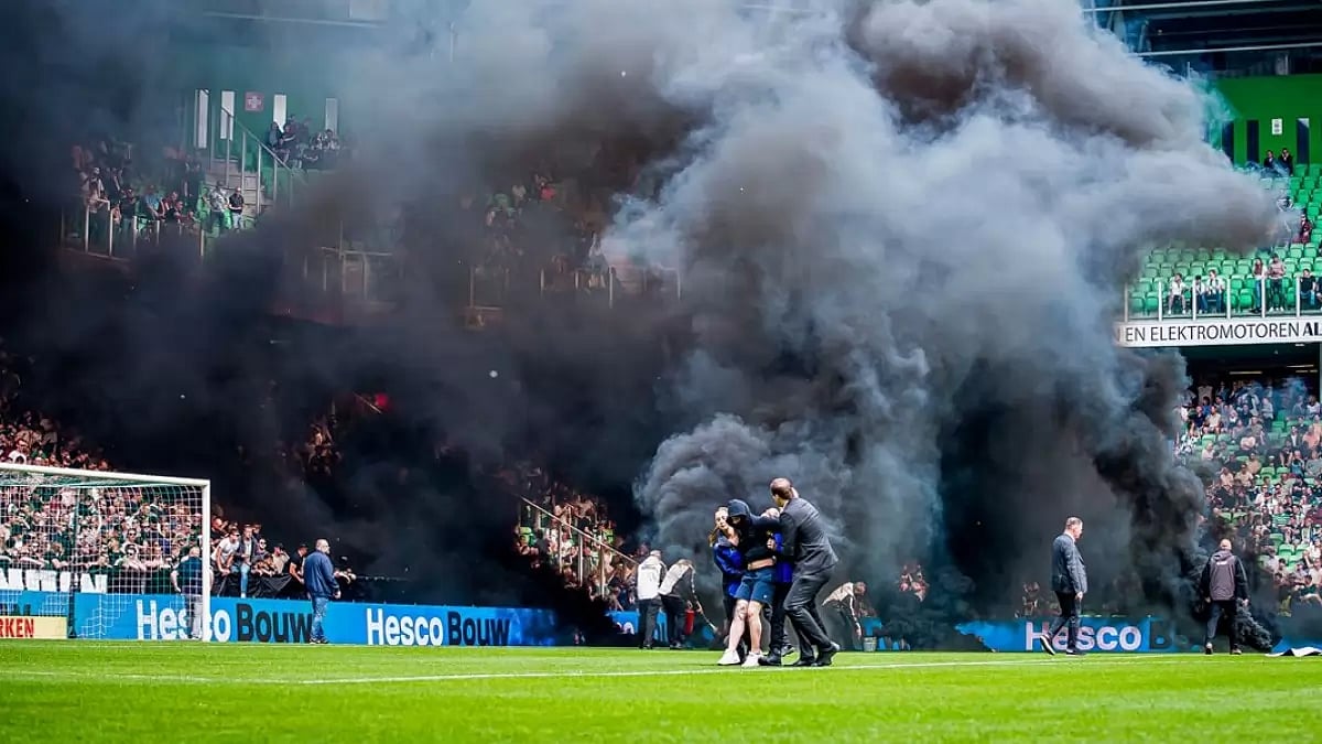 Security nabs fans for disrupting the match with smoke bombs.