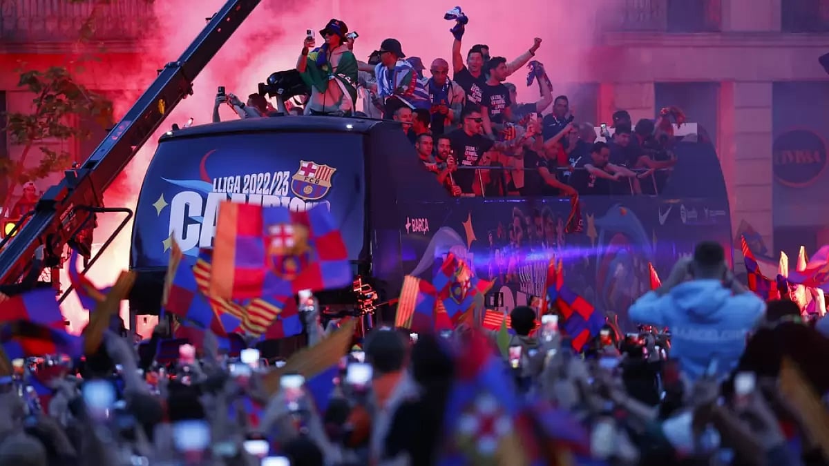 Barcelona players celebrate on the bus during the parade as fans look on.