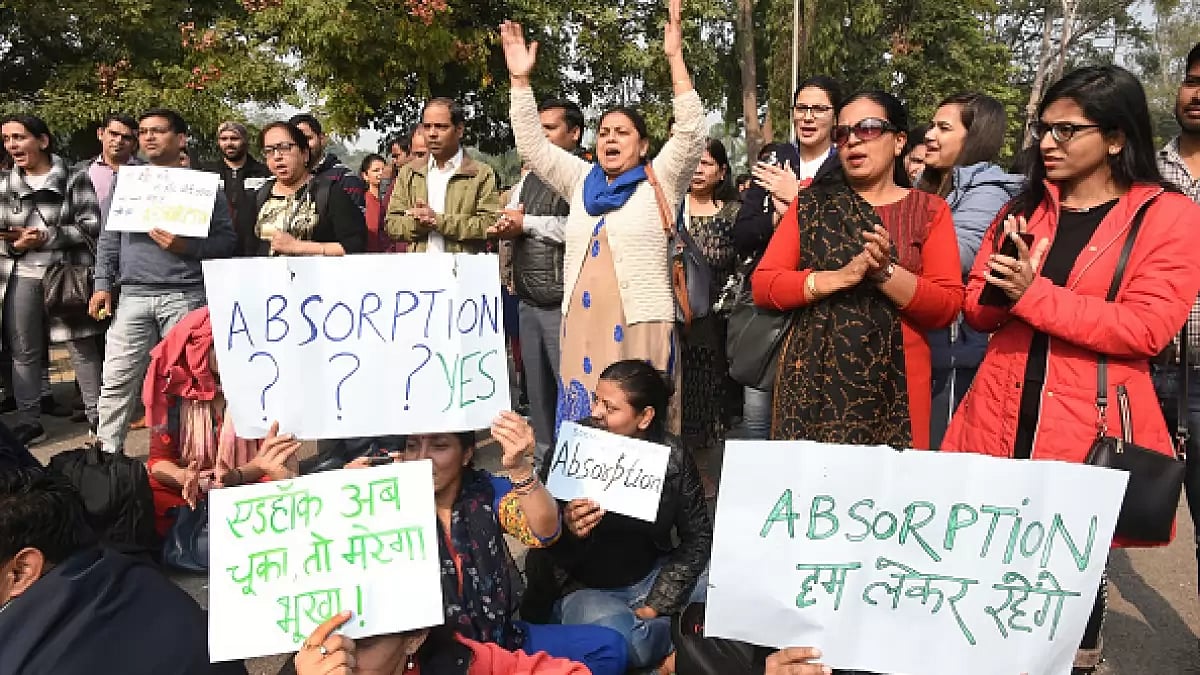 A crowd of protestors hold placards demanding absorption of ad-hoc teachers.
