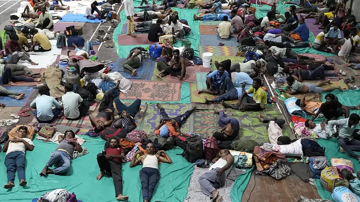 People evacuated from Kandla port, in preparation of Cyclone Biparjoy, rest at a shelter in Gandhidham.