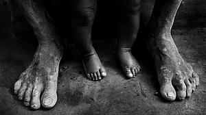 A man, who works at a brick field, holds his baby.