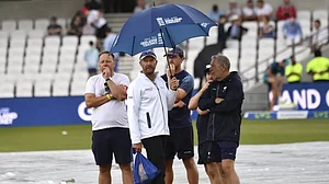 Reserve umpire Mike Burns pictured with the ground staff as the morning session is delayed by rain.