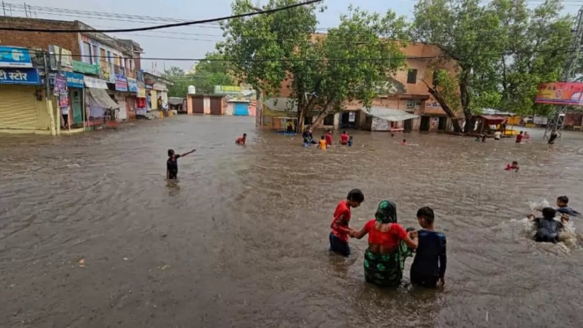 Locals wade through a flooded area after heavy monsoon rains, in Fatehpur  