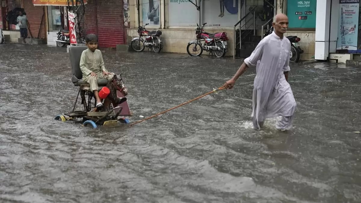 A man wades child through  flood waters in Pakistan's Lahore.