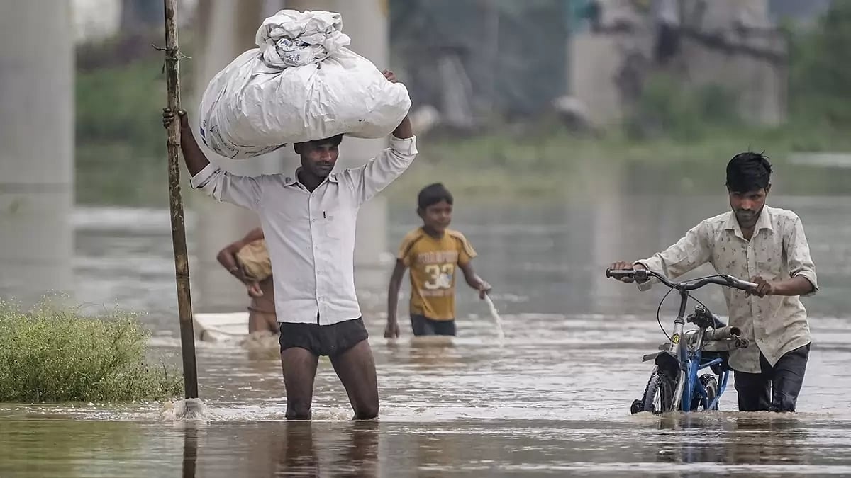 People from low-lying areas around the Yamuna river carry their belongings while relocating to a safer place, in New Delhi. 