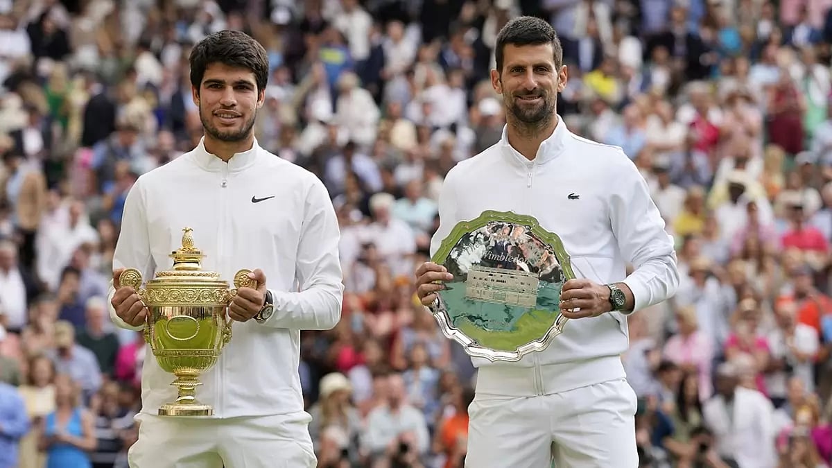 Carlos Alcaraz (l) poses with the trophy after beating Novak Djokovic in the Wimbledon final.