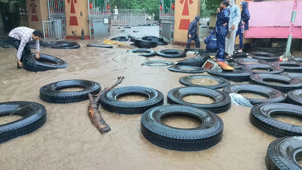 A man places tyres in an inundated area amid a flood-like situation in Junagadh district, Gujarat.