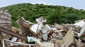 An elderly Muslim man sits on the rubble after his house was demolished following Nuh violence
