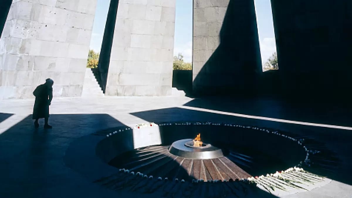 A stooped woman watches the eternal flame at the Armenian Genocide Memorial, Tsitsernakaberd - null