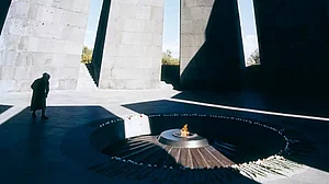 A stooped woman watches the eternal flame at the Armenian Genocide Memorial, Tsitsernakaberd